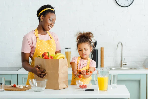 Atractiva Madre Afroamericana Mirando Hija Con Tomates Cherry —  Fotos de Stock