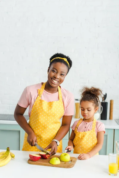 Gelukkig Afrikaans Amerikaans Moeder Glimlachen Terwijl Snijden Appel Buurt Dochter — Stockfoto