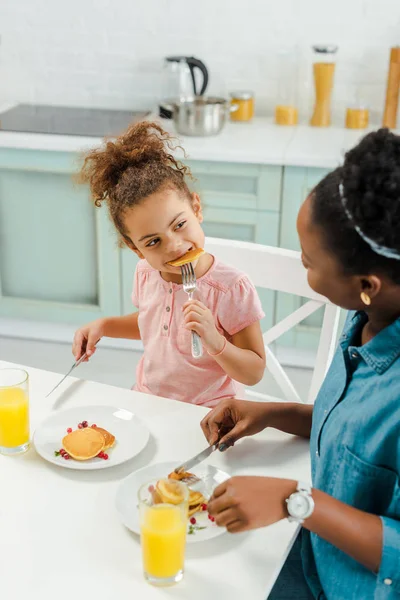 Afrikanisch Amerikanische Mutter Sieht Tochter Leckere Pfannkuchen Essen — Stockfoto