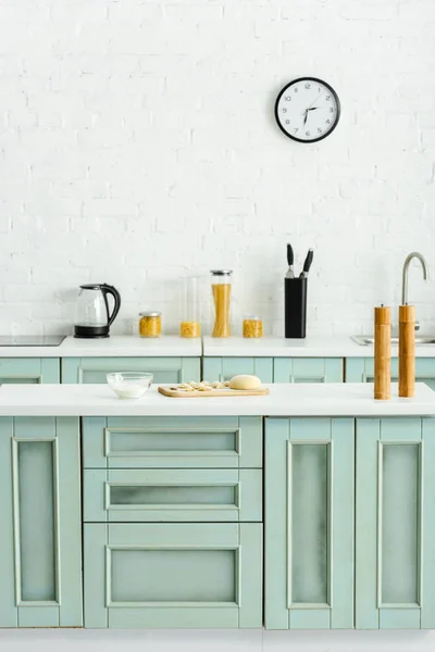 台所に小麦粉とボウルの近くの木製のまな板の上の生餃子 — ストック写真
