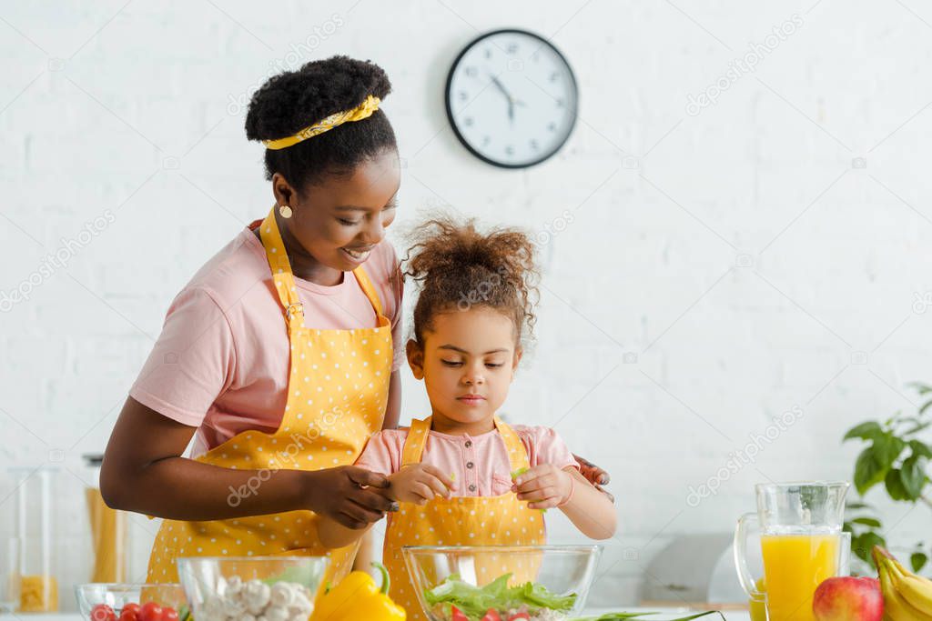 happy african american mother and kid preparing salad 