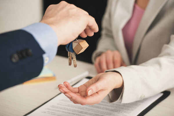 selective focus of realtor giving keys to woman in office 