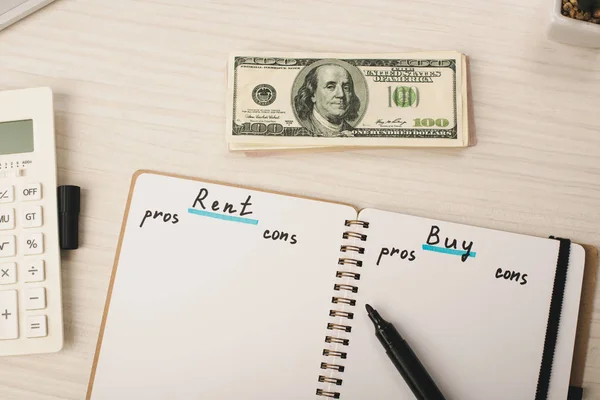 Top view of dollar banknotes near notebook with rent and buy lettering, marker pen and calculator — Stock Image Top View Dollar Banknotes Notebook Rent Buy Lettering Marker Pen Royalty Free Stock Photos