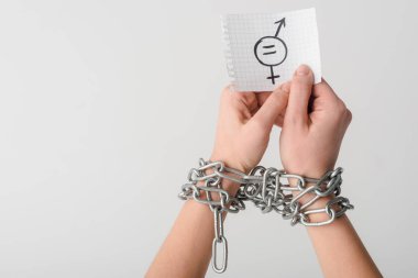Metalik zincirler içinde beyaz, cinsel eşitlik kavramına izole edilmiş cinsiyet sembollü kağıt tutan bir kadın. 