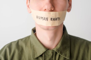 Ağzı koli bandıyla kapatılmış insan hakları yazısı beyaz harflerle izole edilmiş bir adam.