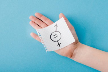 Üzerinde cinsiyet eşitliği sembolü olan kağıt tutan kadının üst görünümü mavi üzerine izole edilmiş 