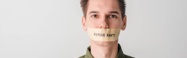 panoramic shot of man with duct tape on mouth with human rights lettering isolated on white