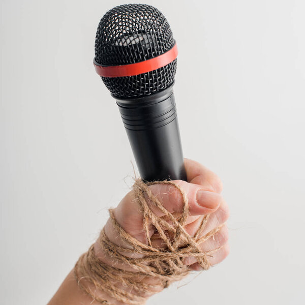 cropped view of woman with tied hand holding microphone isolated on white, freedom of speech concept 