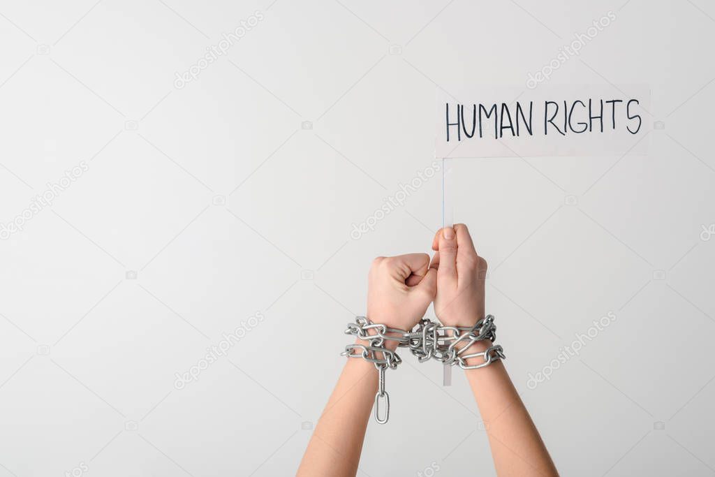 cropped view of woman in metallic chains holding flag with human rights lettering isolated on white