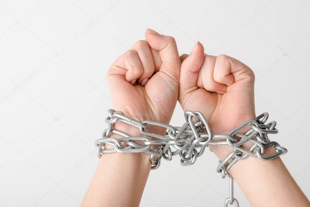 cropped view of young woman in metallic chains isolated on white, human rights concept 