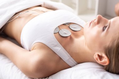 Klinikteki göğüs elektrot tedavisi sırasında masaj koltuğuna uzanan çekici kadının seçici odağı