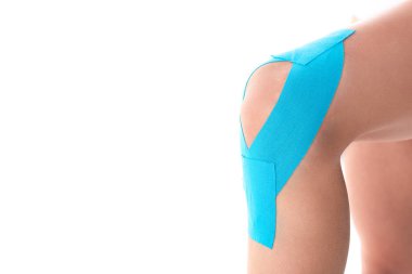 Cropped view of kinesiology tapes on knee of woman isolated on white clipart