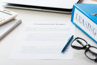 selective focus of folder near document with commercial lease lettering on desk  clipart