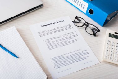 En üst klasör, hesap makinesi, kalem ve gözlük görünümü masanın üzerinde ticari kiralama antetli belge yanında 