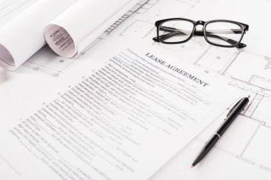 document with lease agreement lettering near glasses, blueprints and pen on desk  clipart