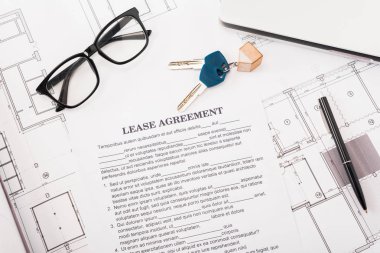 top view of document with lease agreement lettering near glasses, blueprints and keys on desk  clipart