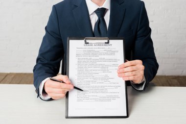 cropped view of realtor holding clipboard with lease agreement lettering on document 