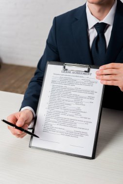 cropped view of agent holding clipboard with lease agreement lettering and pen clipart