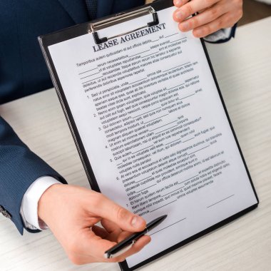cropped view of businessman holding clipboard with lease agreement lettering and pen 