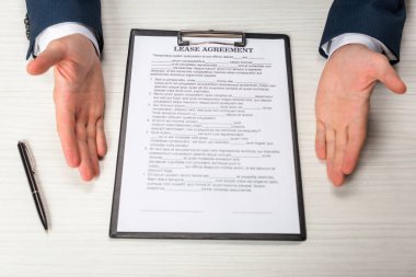 cropped view of businessman near clipboard with lease agreement lettering and pen  clipart