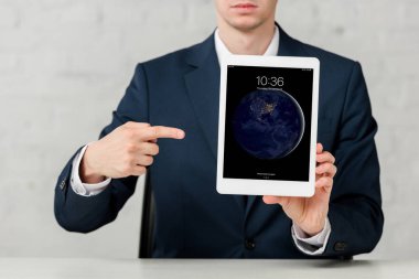 cropped view of realtor in suit pointing with finger at ipad on white 