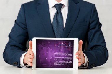 cropped view of man in suit holding digital tablet with medical app on white 