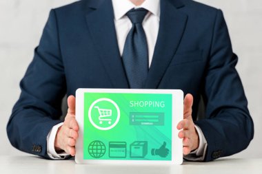 cropped view of businessman holding digital tablet with online shopping on screen on white 