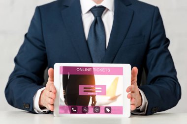 cropped view of businessman holding digital tablet with online tickets on screen on white 