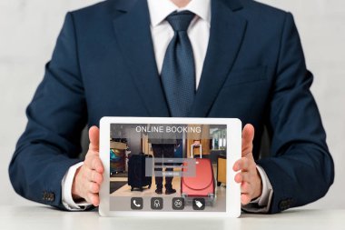 cropped view of businessman holding digital tablet with online booking on screen on white 