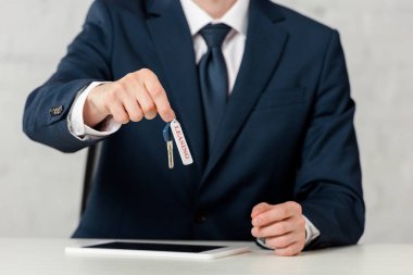 cropped view of businessman holding key with leasing lettering near digital tablet on white 