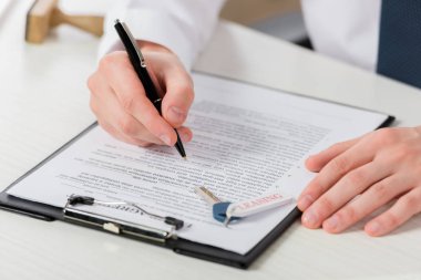 cropped view of businessman holding pen near clipboard with document and key with leasing lettering 
