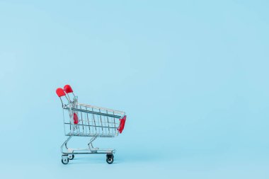 empty toy shopping cart on blue with copy space, leasing concept
