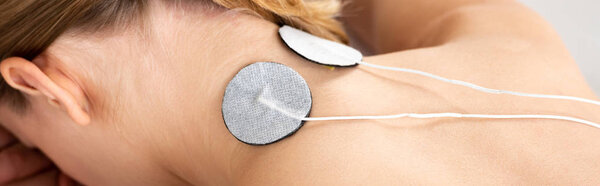 Panoramic shot of stimulation electrodes on female neck isolated on grey