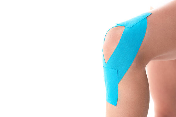 Cropped view of kinesiology tapes on knee of woman isolated on white