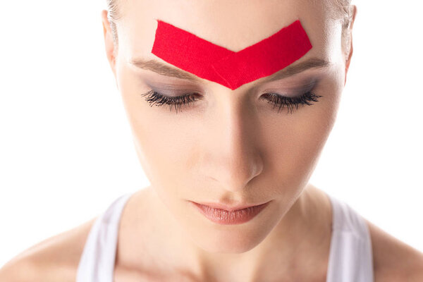 Beautiful girl with kinesiology tapes on forehead isolated on white