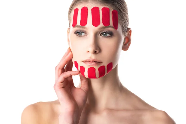 Young woman with kinesiology tapes on face looking away isolated on white