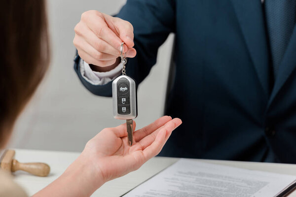 cropped view of realtor giving key to client, leasing concept