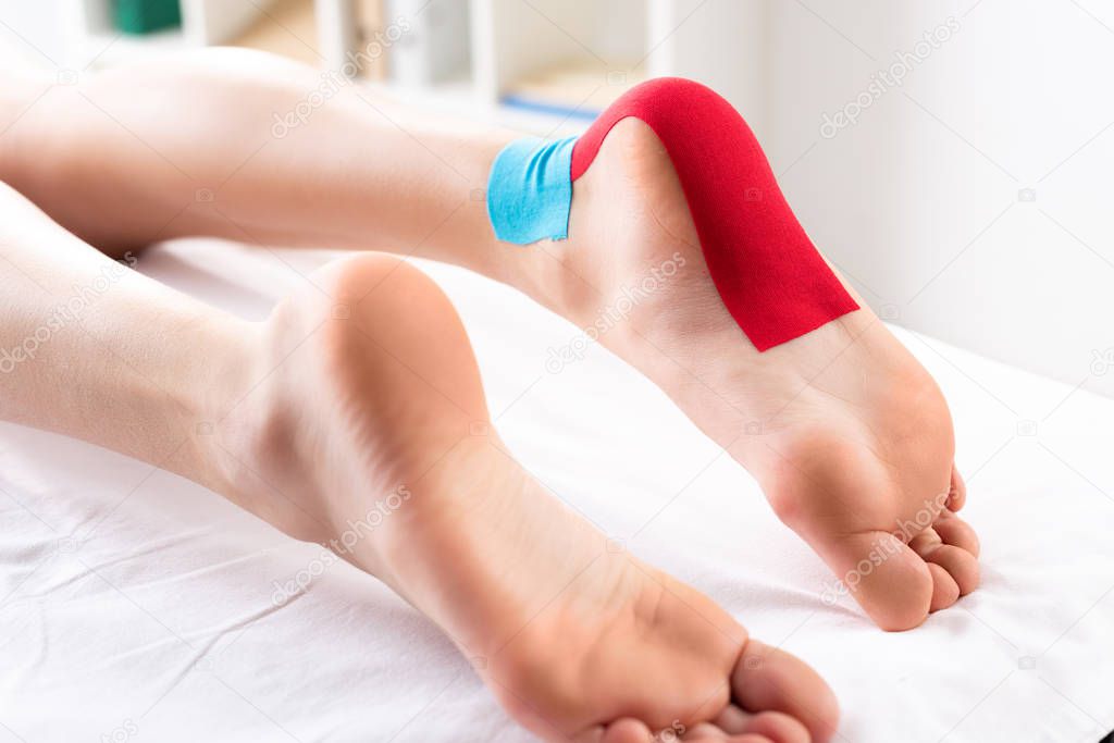 Cropped view of woman lying on massage couch with kinesiology tapes on foot
