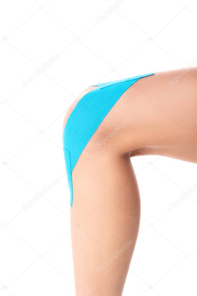 Cropped view of female knee with kinesiology tapes isolated on white