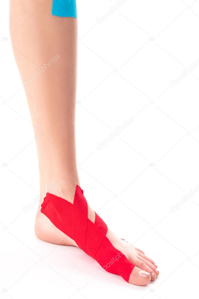 Cropped view of female leg with kinesiology tapes on white background