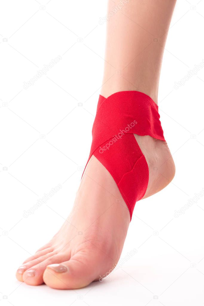 Cropped view of kinesiology tapes on foot of woman on white background