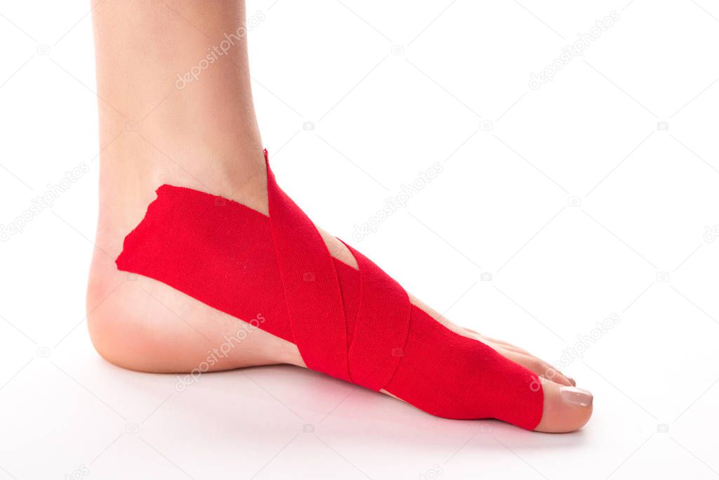 Cropped view of woman foot with kinesiology tapes on white background