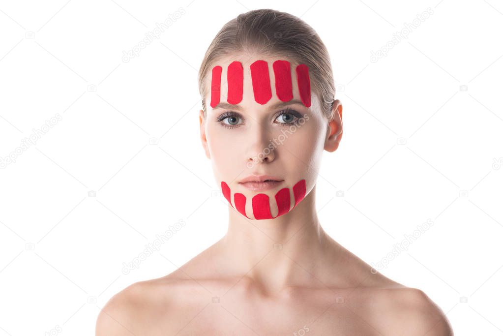 Attractive young woman with kinesiology tapes on forehead and chin looking at camera isolated on white