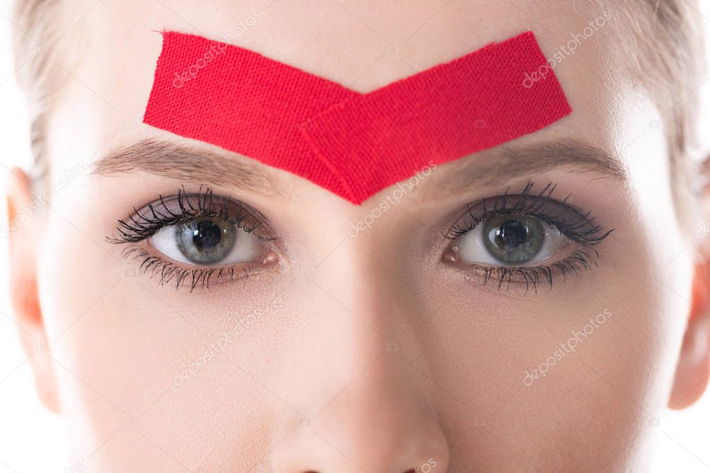 Cropped view of girl with kinesiology tapes on forehead looking at camera isolated on white