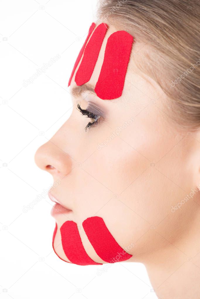 Side view of kinesiology tapes on face of beautiful girl isolated on white