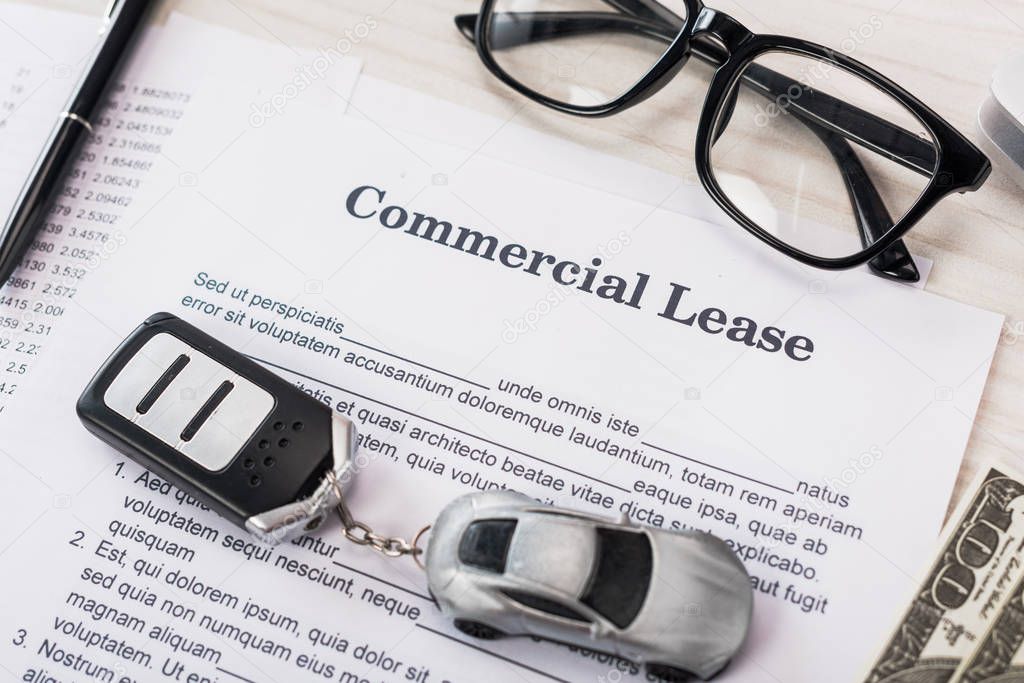 top view of document with commercial lease lettering near toy car, money and glasses