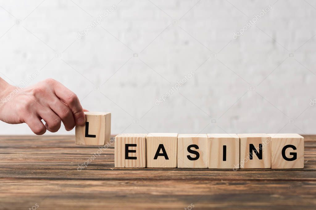 cropped view of man holding cube with lettering on white 