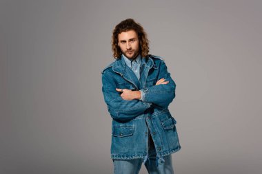 Kot ceketli şık bir adam ve kolları çapraz olan kot pantolon gri renkte izole edilmiş.