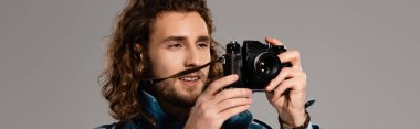 Gri üzerinde izole edilmiş fotoğraf çeken gülümseyen adamın panoramik görüntüsü