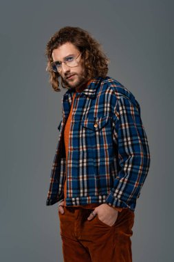 Gri gömlekli yakışıklı adam kameraya bakıyor.